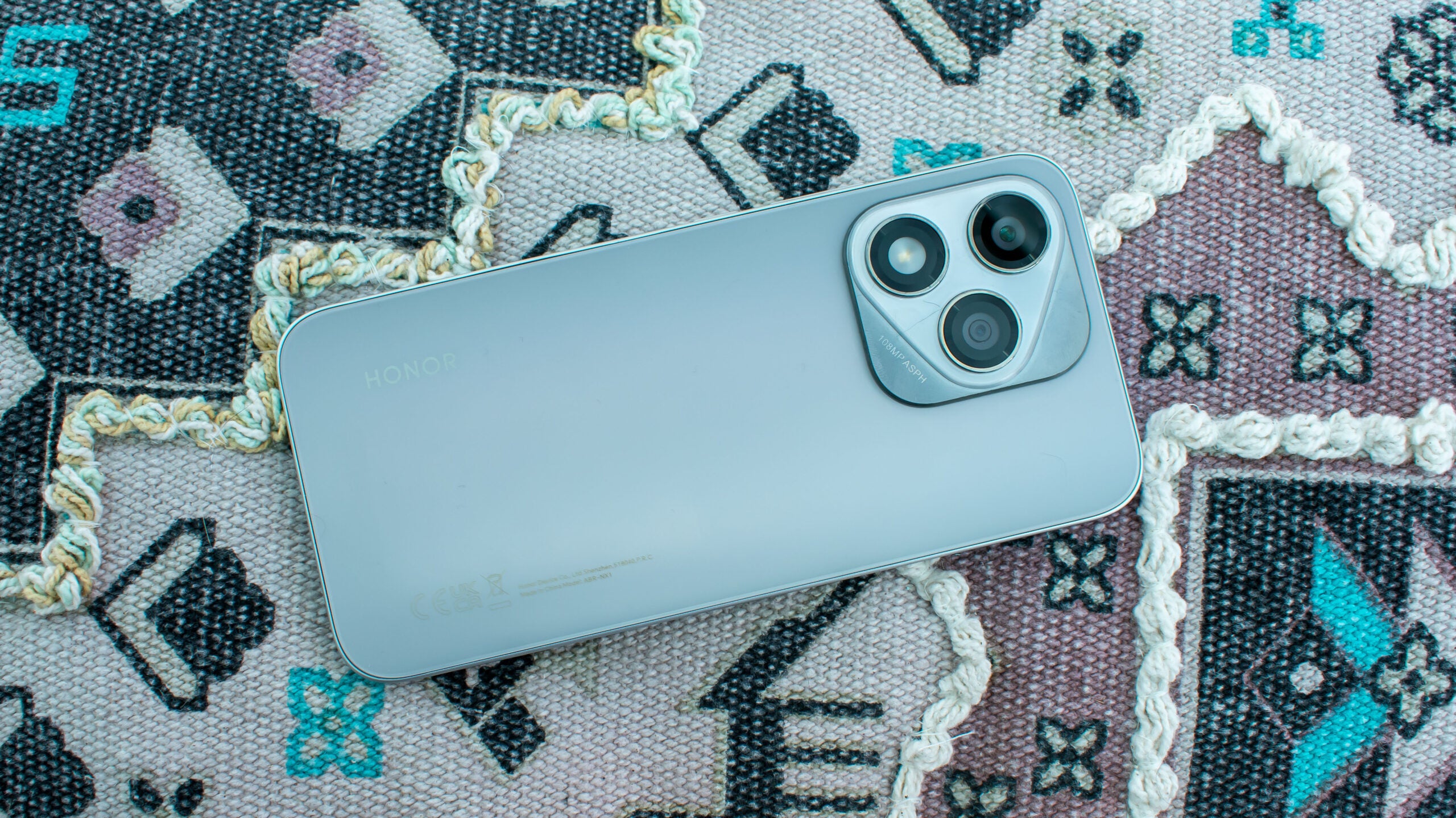 Honor 400 Lite лежит экраном вниз на узорчатой подушке