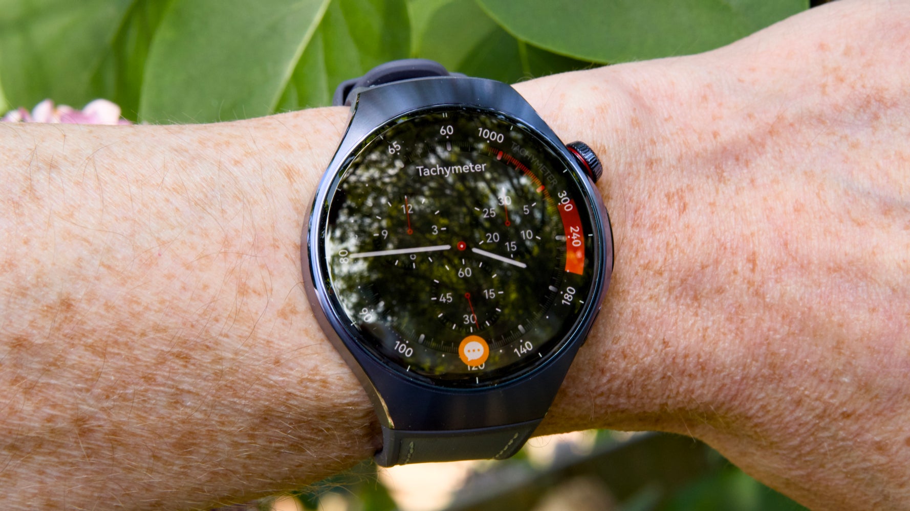 Huawei Watch 5 на запястье с зеленью на заднем плане