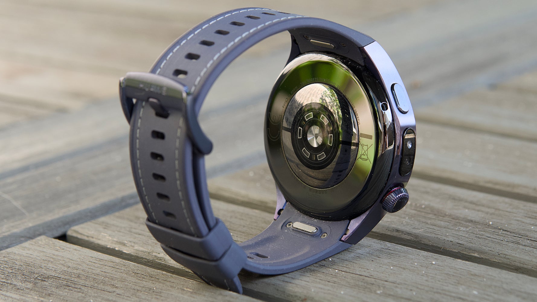 Задняя часть Huawei Watch 5, изображенная на садовом столе